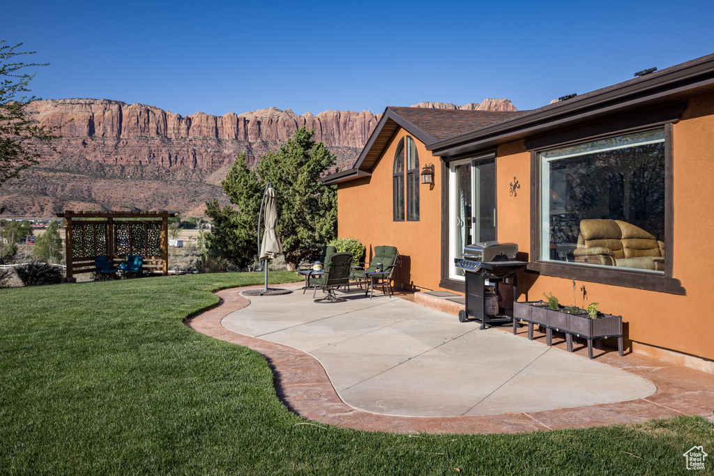 Exterior space with a mountain view, a lawn, and a patio