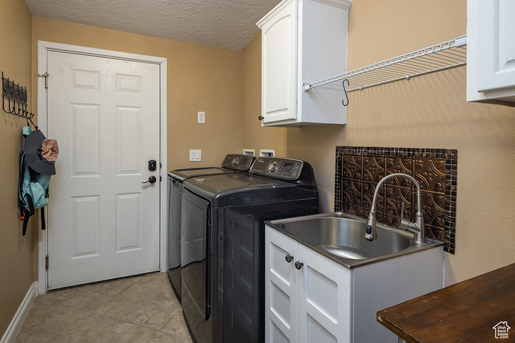 Washroom featuring separate washer and dryer, hookup for a washing machine, cabinets, sink, and light tile flooring