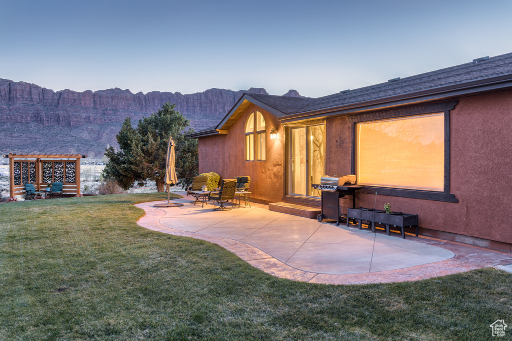 Exterior space featuring a mountain view, a lawn, and a patio area