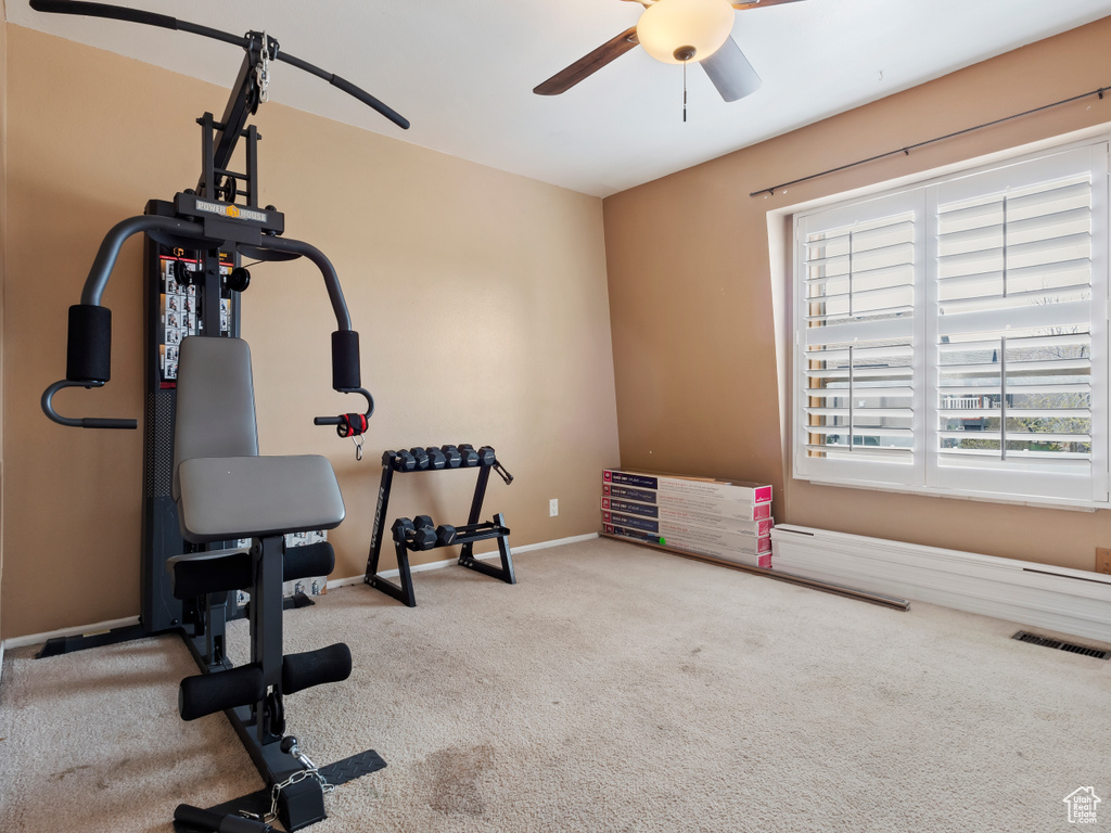 Workout area with ceiling fan and light colored carpet