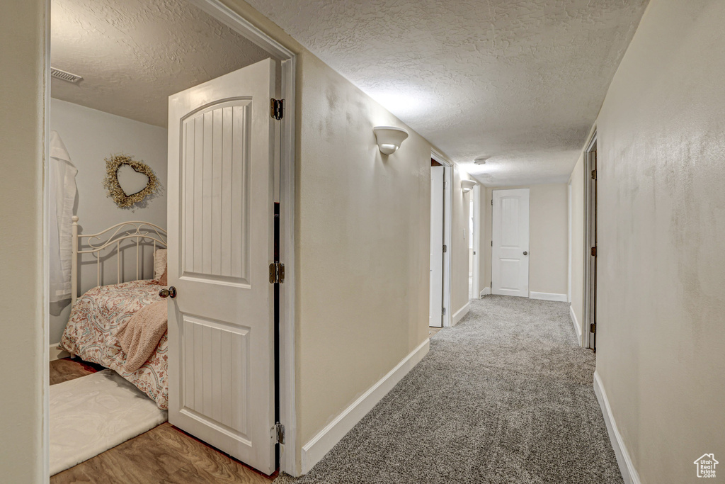 Corridor with a textured ceiling and light colored carpet