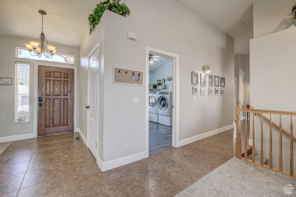 Entrance foyer featuring washer and clothes dryer, hardwood / wood-style flooring, and ceiling fan with notable chandelier
