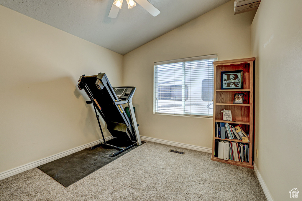 Workout area with lofted ceiling, light colored carpet, and ceiling fan