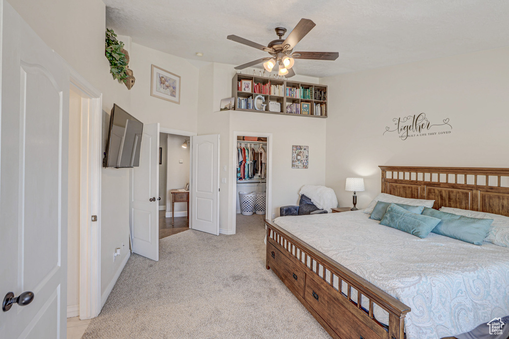 Bedroom with light carpet, a spacious closet, a closet, and ceiling fan