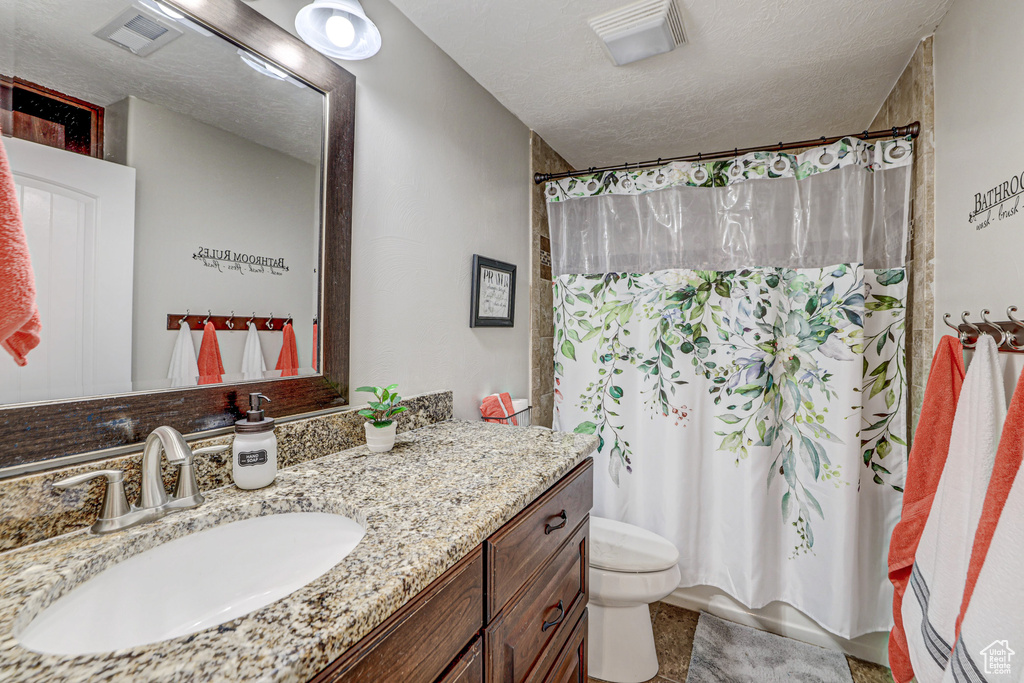 Bathroom featuring tile floors, toilet, vanity, and a textured ceiling