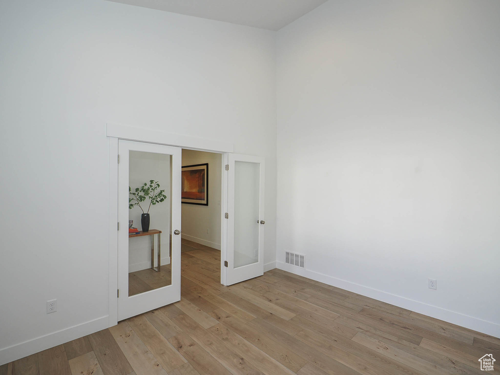 Unfurnished room with french doors and light hardwood / wood-style floors