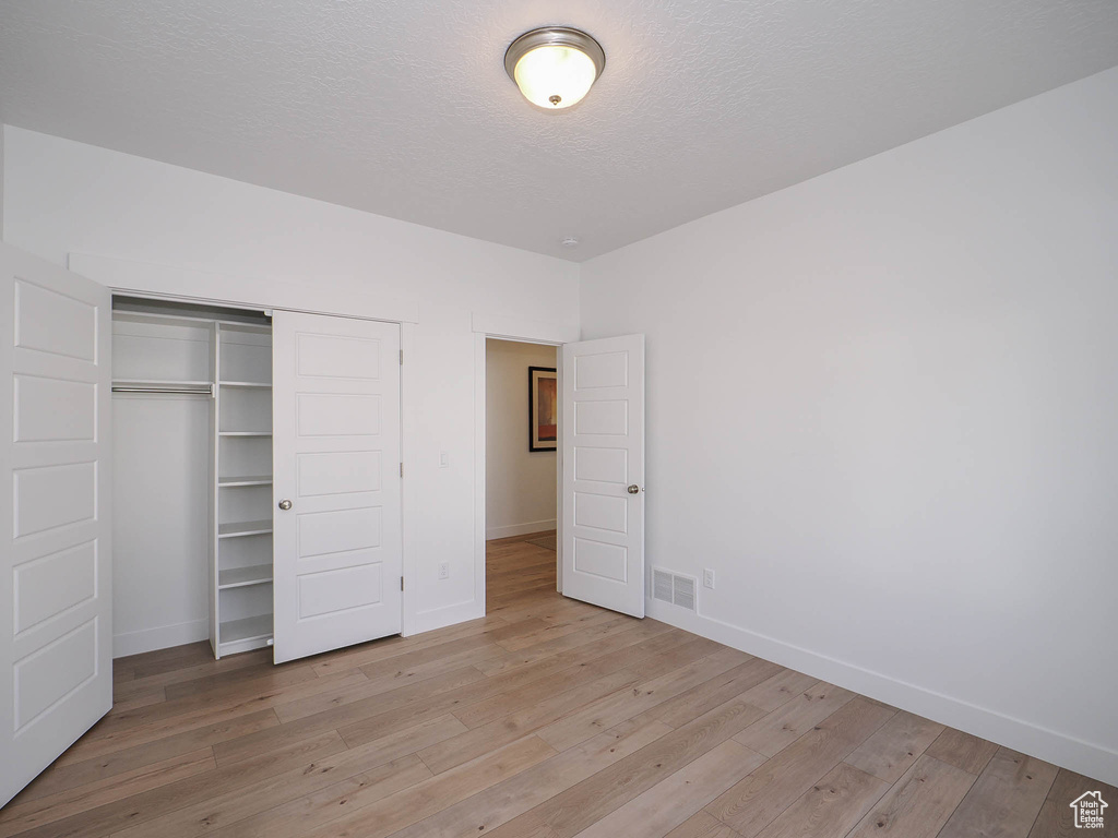 Unfurnished bedroom with a closet and light hardwood / wood-style flooring