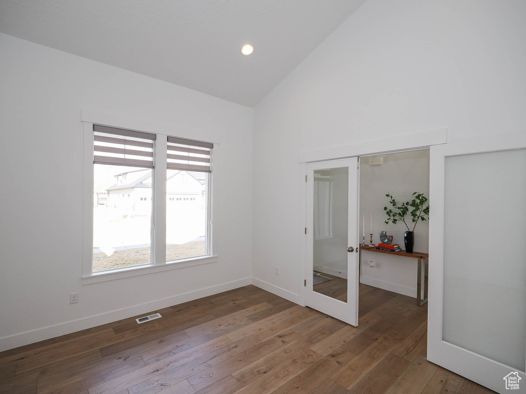 Empty room featuring french doors, vaulted ceiling, and dark hardwood / wood-style floors