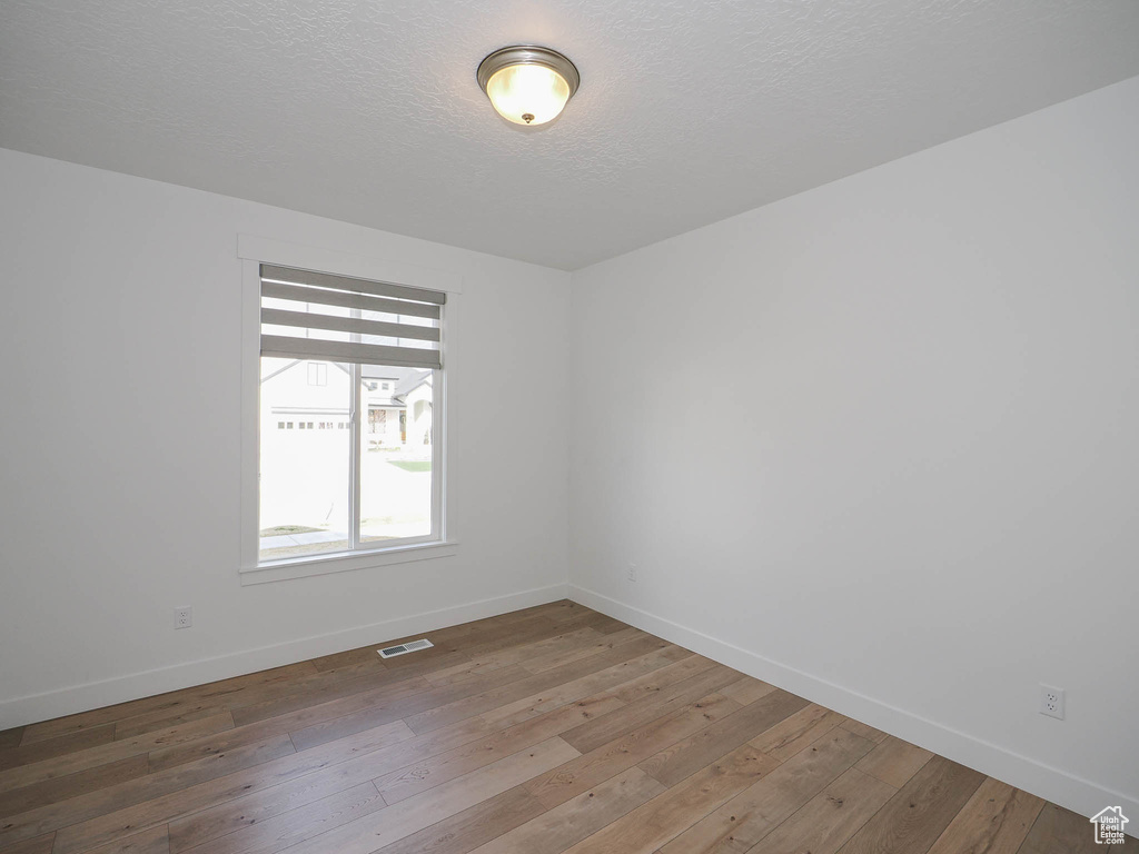 Spare room with a textured ceiling and hardwood / wood-style flooring