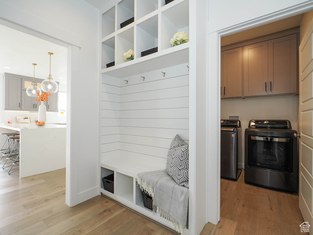 Mudroom with washing machine and clothes dryer, a chandelier, and light hardwood / wood-style floors