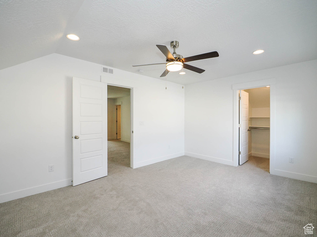 Unfurnished bedroom featuring a spacious closet, a closet, ceiling fan, and light colored carpet