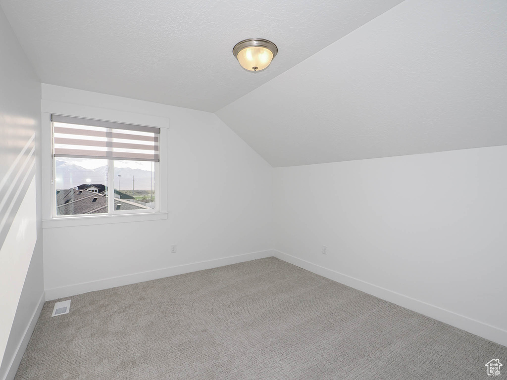 Additional living space with lofted ceiling and light colored carpet