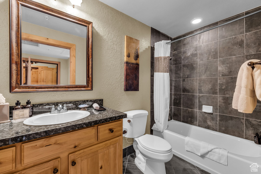 Full bathroom featuring toilet, tile floors, vanity, and shower / bath combination with curtain