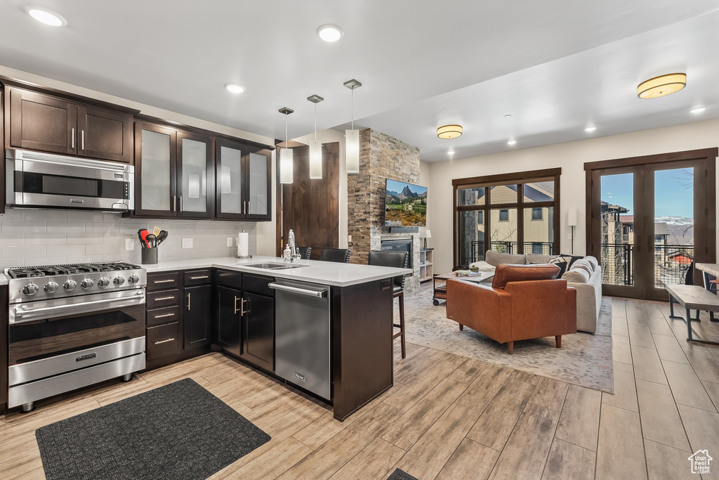 Kitchen featuring decorative light fixtures, light hardwood / wood-style floors, appliances with stainless steel finishes, and backsplash