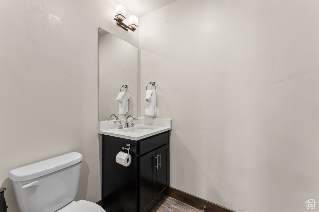 Bathroom with hardwood / wood-style floors, oversized vanity, and toilet