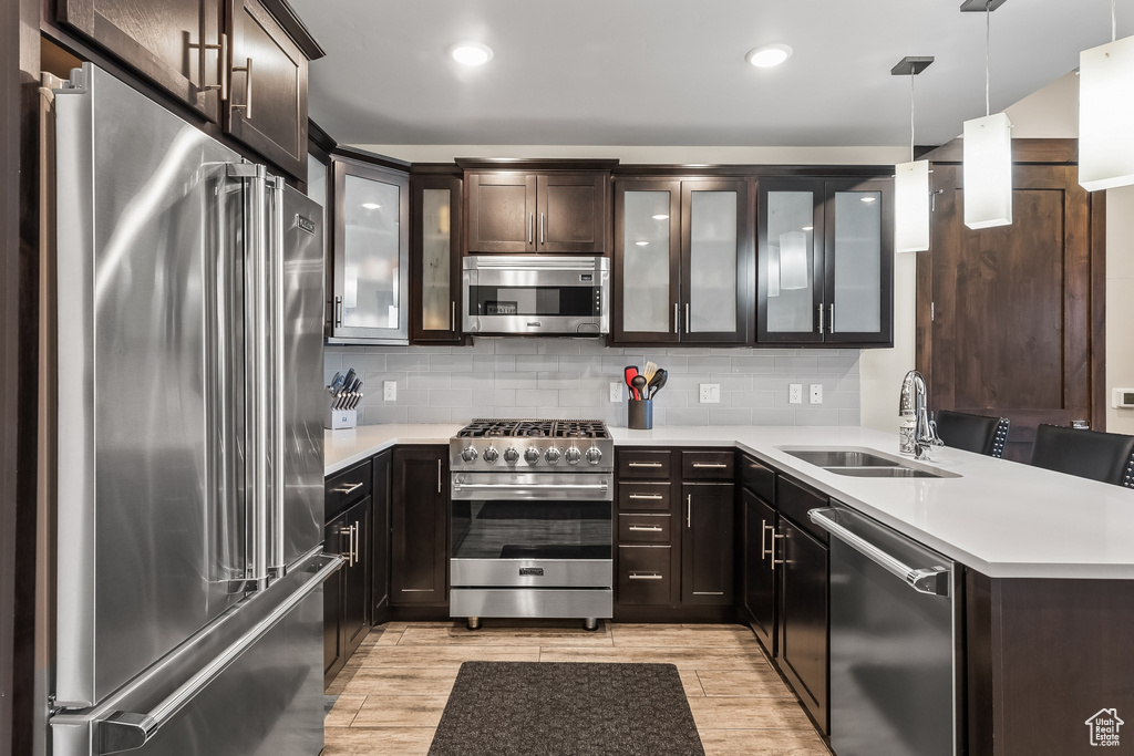 Kitchen featuring hanging light fixtures, tasteful backsplash, sink, and high end appliances