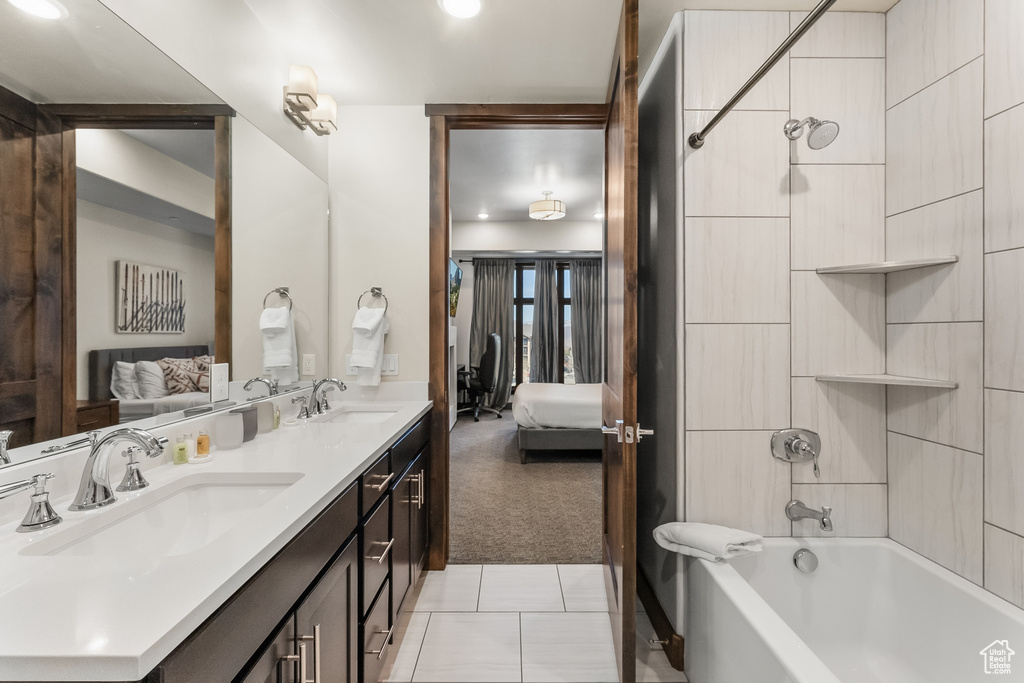 Bathroom featuring dual bowl vanity, tiled shower / bath, and tile flooring