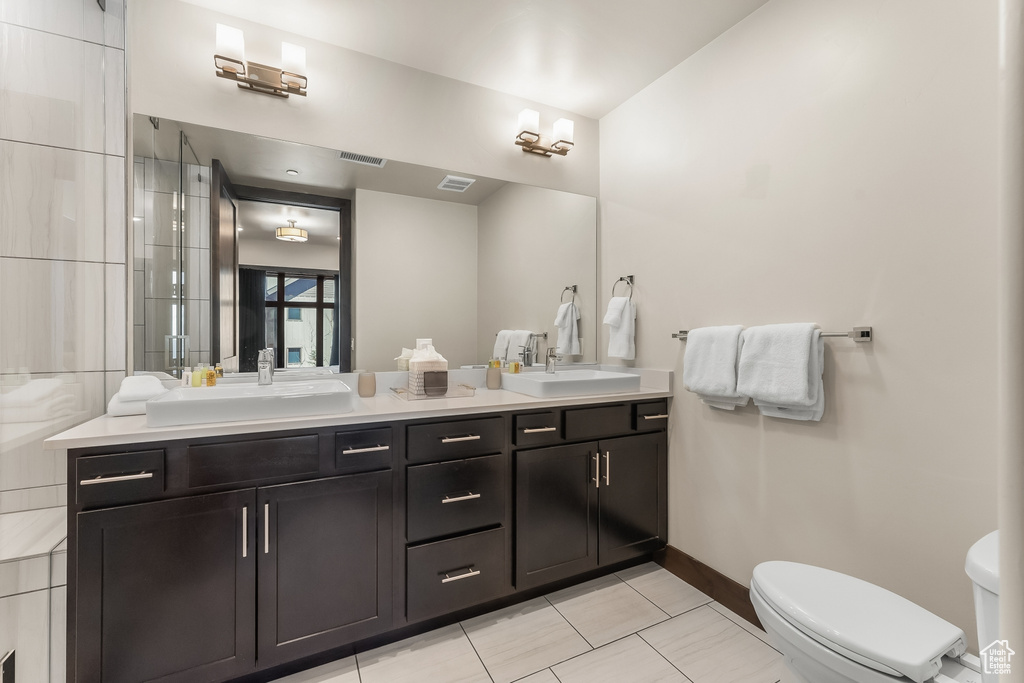 Bathroom featuring toilet, tile floors, and dual vanity