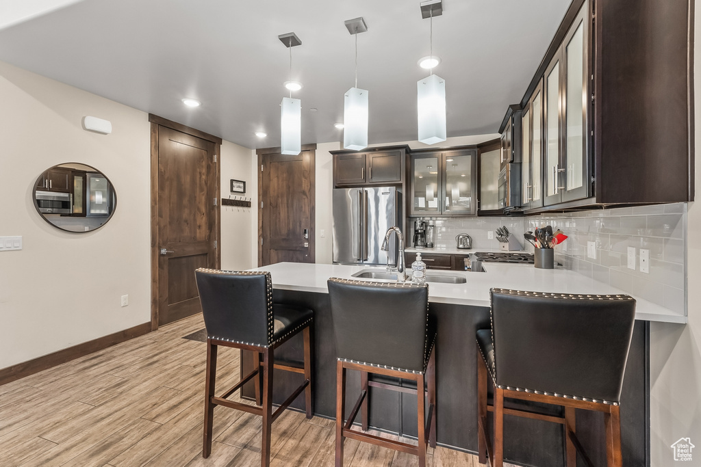 Kitchen with backsplash, high end fridge, a breakfast bar, and light wood-type flooring