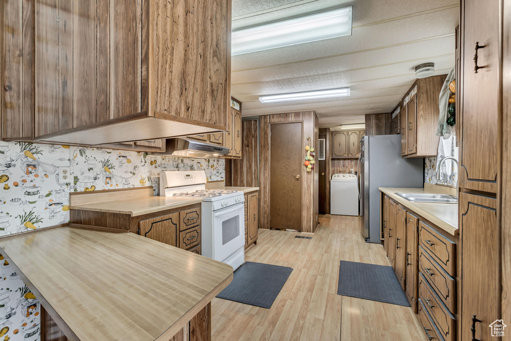 Kitchen featuring washer / clothes dryer, light hardwood / wood-style floors, sink, and white range oven