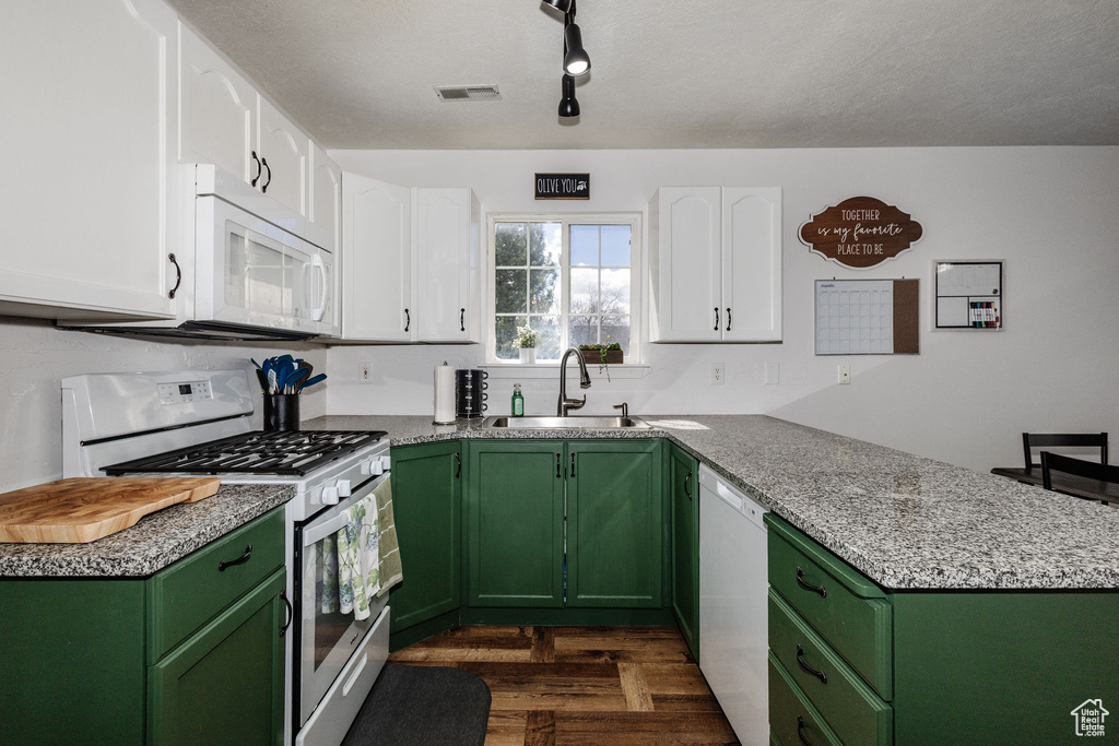Kitchen featuring rail lighting, green cabinetry, white appliances, white cabinets, and sink