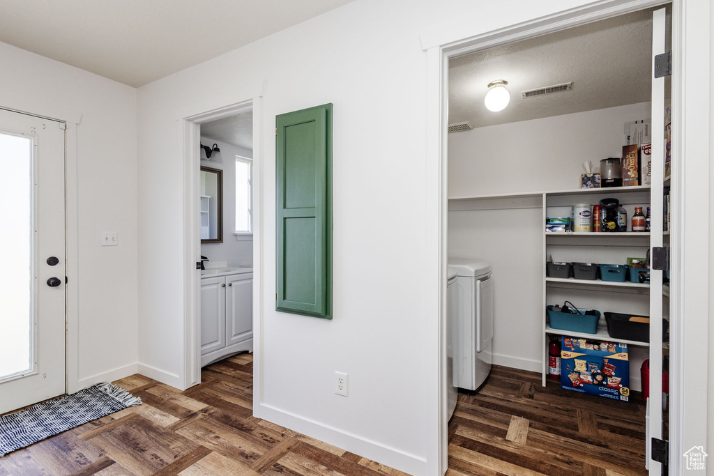 Laundry area with plenty of natural light, dark parquet floors, independent washer and dryer, and sink