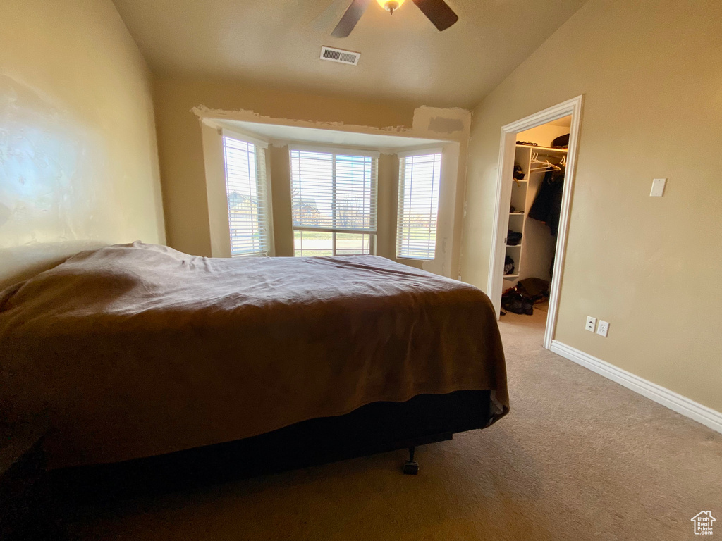 Bedroom featuring light colored carpet, a closet, ceiling fan, lofted ceiling, and a walk in closet