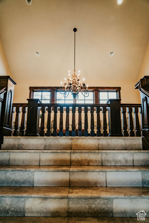Stairs with an inviting chandelier and high vaulted ceiling