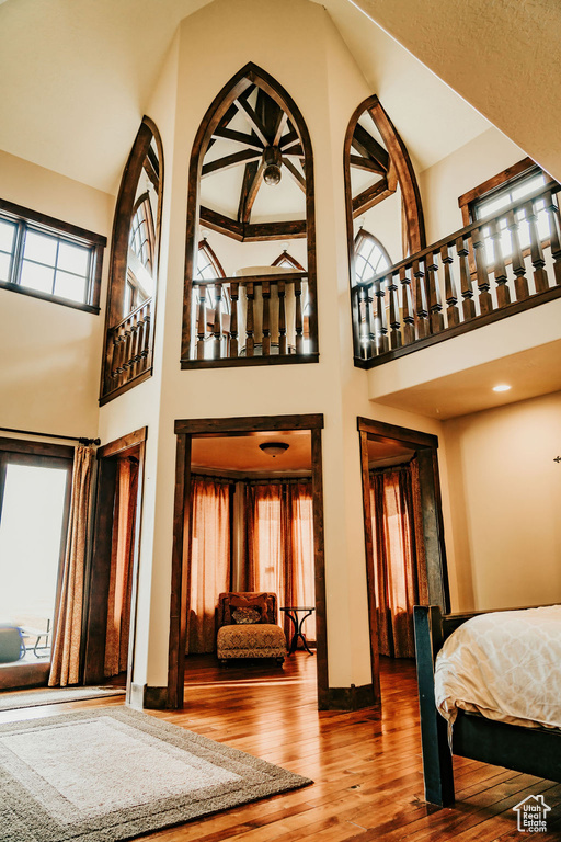 Bedroom featuring hardwood / wood-style floors, high vaulted ceiling, and multiple windows