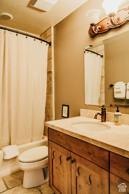 Full bathroom featuring oversized vanity, toilet, a textured ceiling, and shower / bath combo with shower curtain
