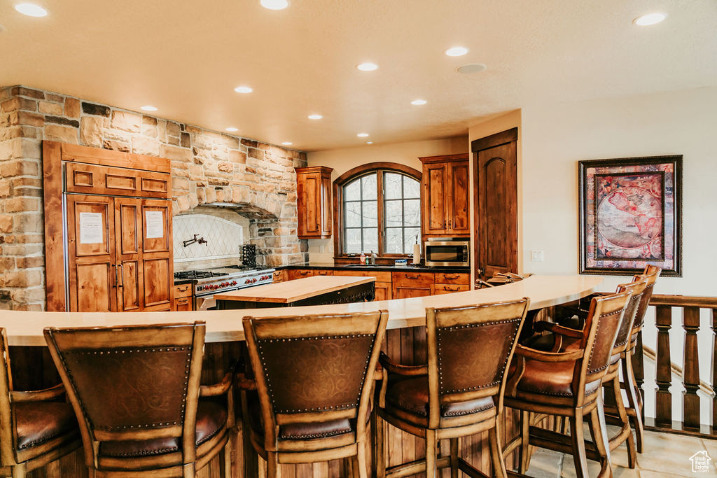Kitchen featuring a kitchen bar, a center island, stainless steel appliances, and sink