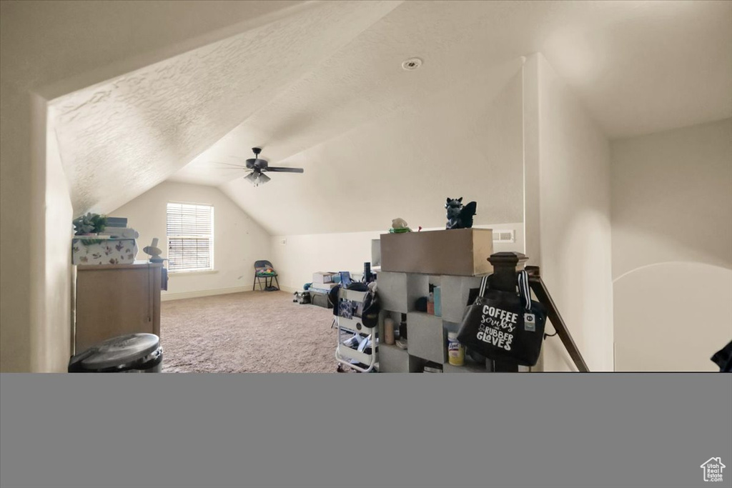 Interior space featuring lofted ceiling, a textured ceiling, ceiling fan, and carpet floors