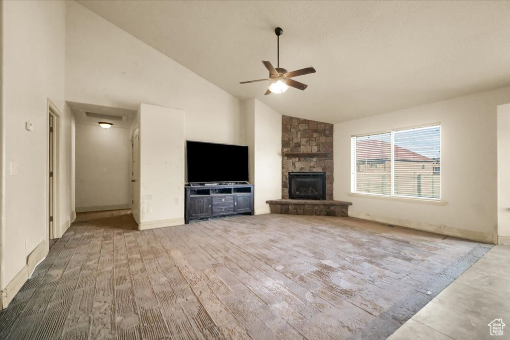 Unfurnished living room with hardwood / wood-style floors, ceiling fan, high vaulted ceiling, and a fireplace