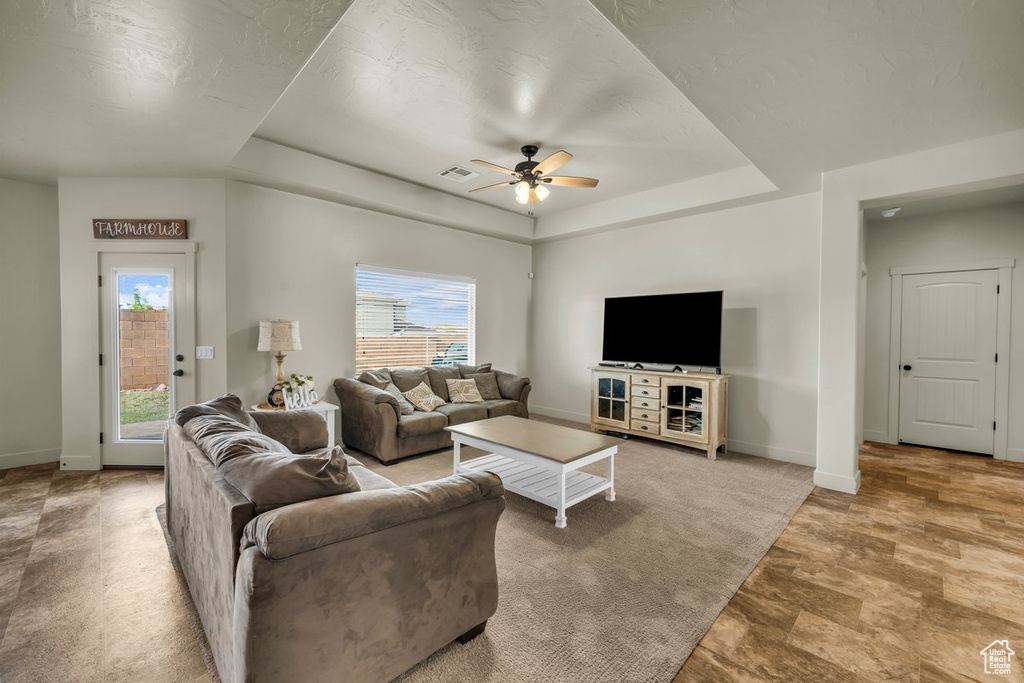 Living room with ceiling fan and a raised ceiling