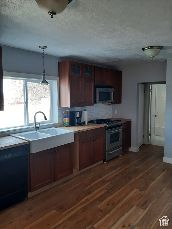 Kitchen with dark wood-type flooring, sink, and stainless steel appliances