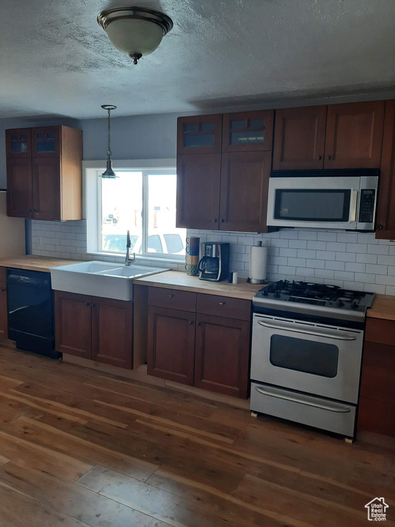 Kitchen featuring backsplash, dishwasher, gas stove, and dark wood-type flooring