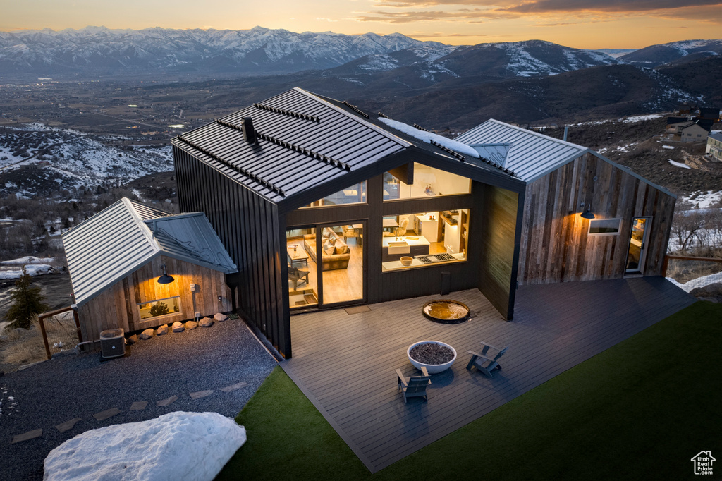 Back house at dusk featuring a deck with mountain view and an outdoor structure