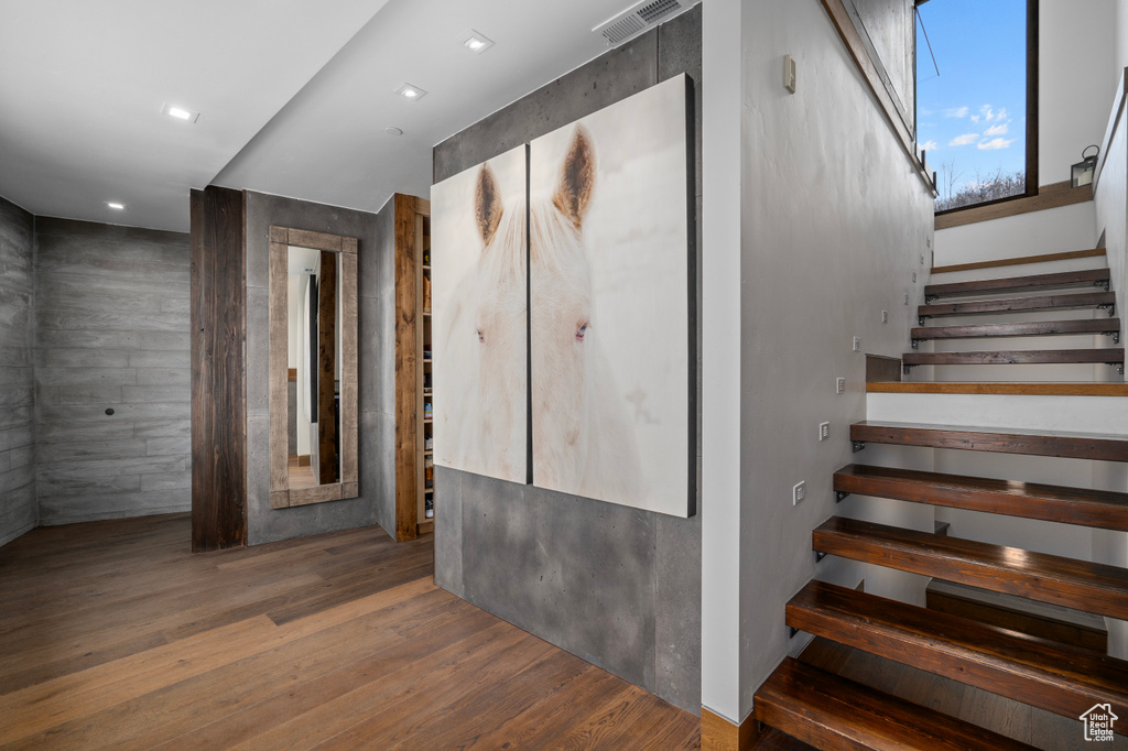 Stairway with dark wood-type flooring and tile walls