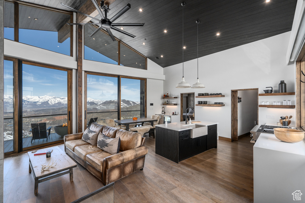 Living room with dark hardwood / wood-style floors, ceiling fan, high vaulted ceiling, a mountain view, and sink