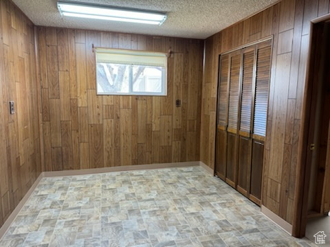 Empty room featuring a textured ceiling and wooden walls