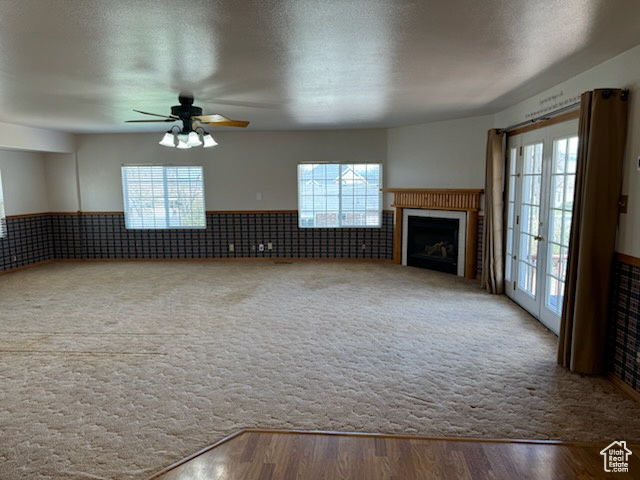 Unfurnished living room with ceiling fan, light colored carpet, and french doors