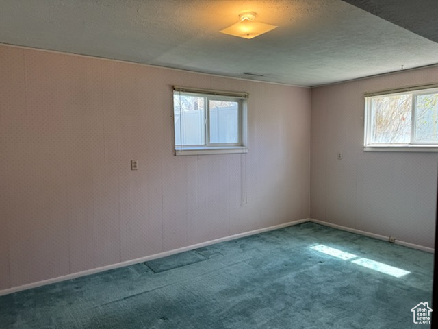 Empty room featuring a textured ceiling and dark carpet