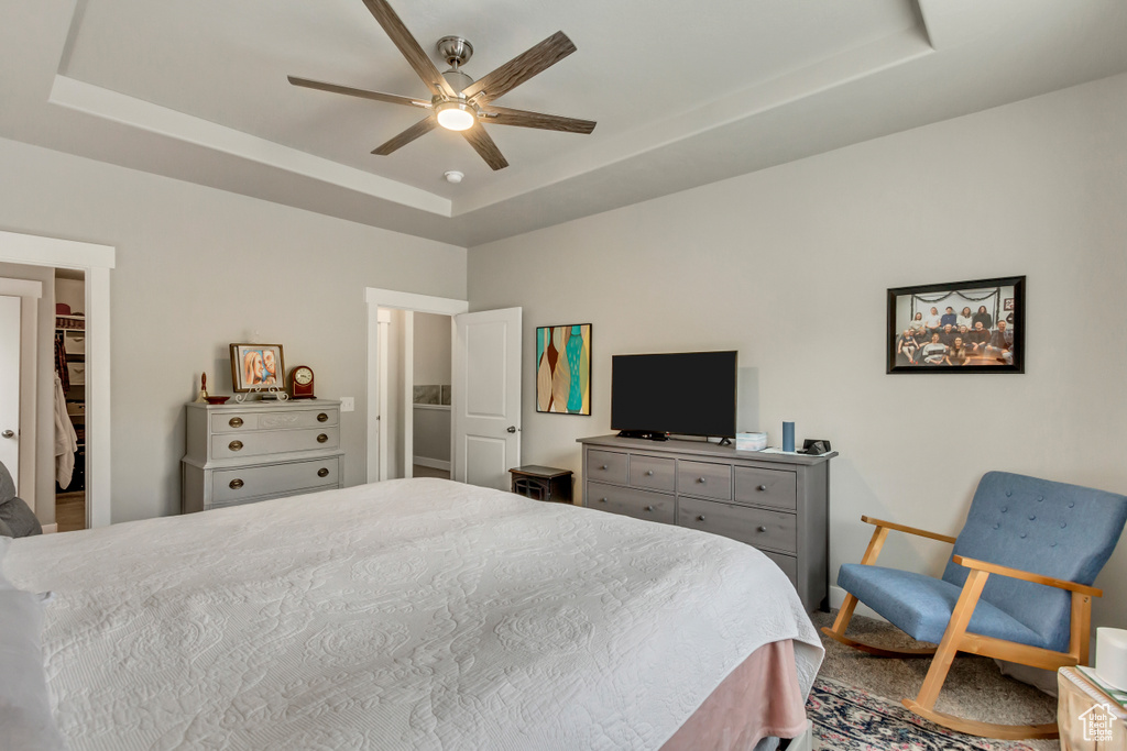 Bedroom featuring a tray ceiling, a spacious closet, and ceiling fan