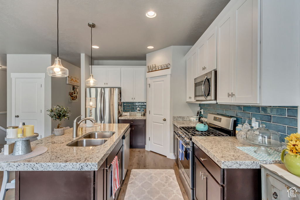 Kitchen featuring appliances with stainless steel finishes, sink, a center island with sink, and white cabinets