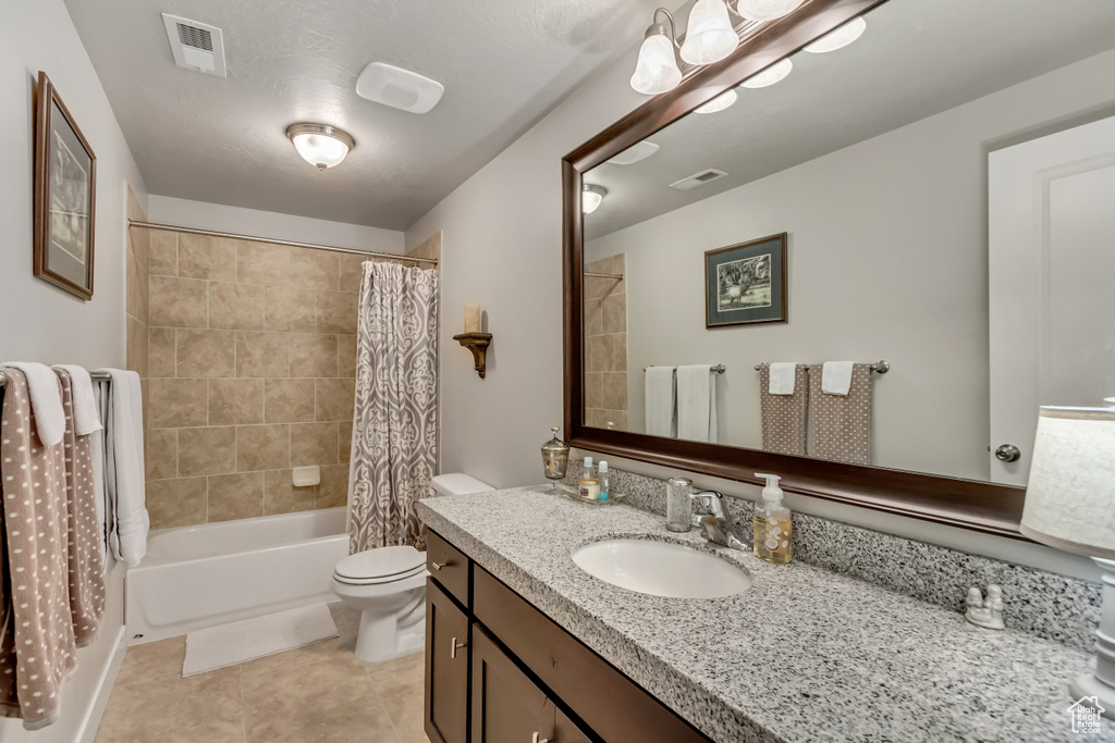 Full bathroom featuring tile flooring, large vanity, toilet, and shower / bathtub combination with curtain