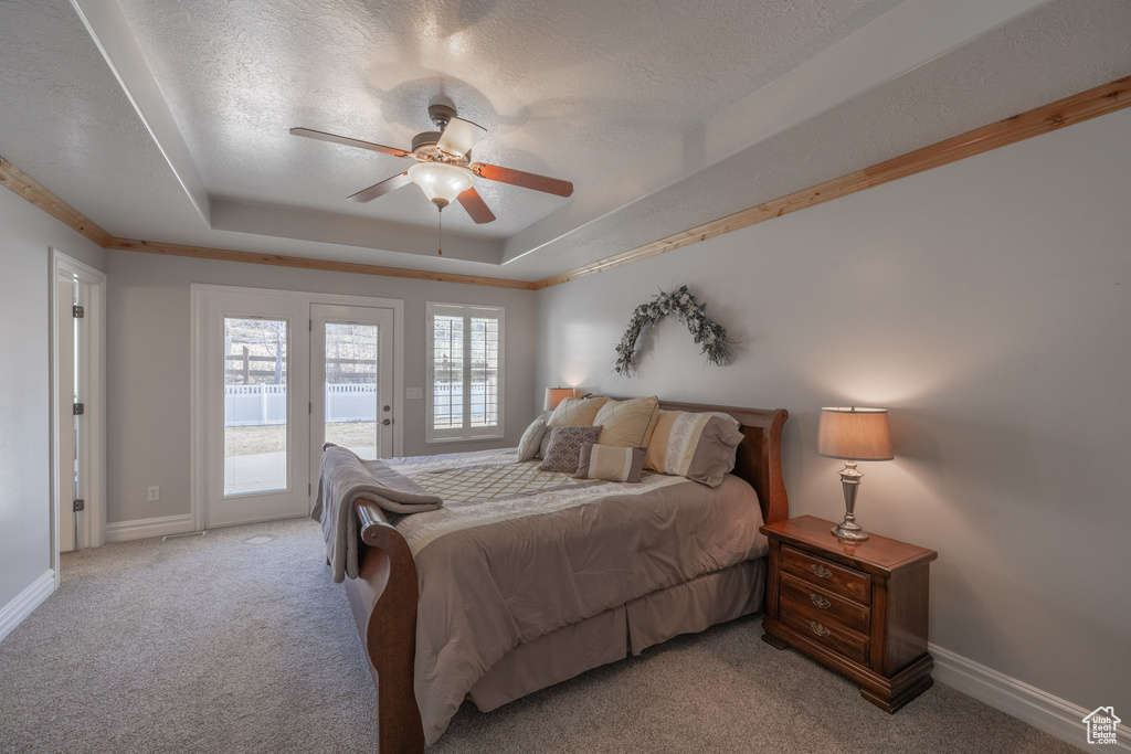 Carpeted bedroom with ceiling fan, access to exterior, a tray ceiling, and a textured ceiling