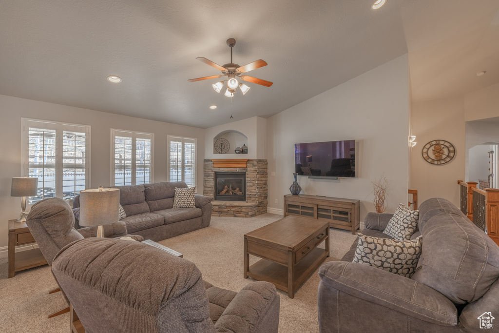 Living room with light carpet, ceiling fan, a stone fireplace, and lofted ceiling