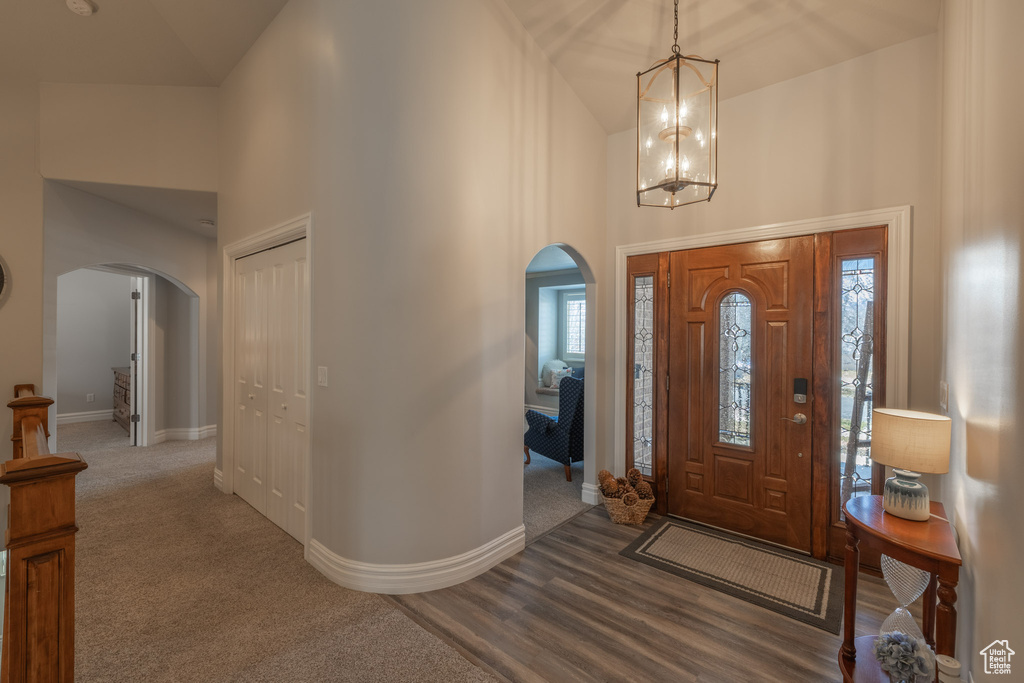 Carpeted entryway featuring high vaulted ceiling and an inviting chandelier