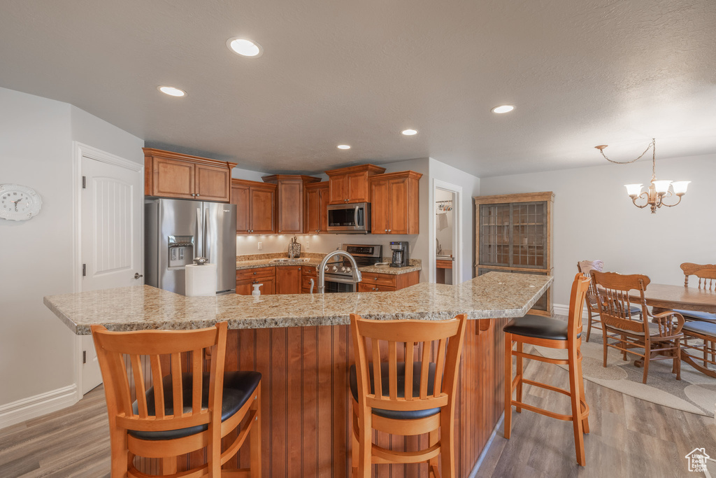 Kitchen featuring a kitchen bar, hardwood / wood-style floors, stainless steel appliances, and a notable chandelier