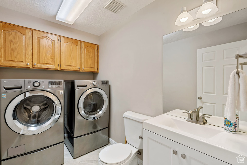 Clothes washing area featuring washer and dryer and a textured ceiling